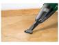 Aspirateur à main nettoyant un déversement de liquide sur une surface en bois.