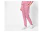 Une femme porte un pantalon de survêtement rose et des baskets blanches.