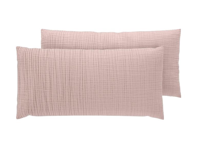 Deux taies d'oreiller en mousseline rose clair avec un motif quadrillé subtil, l'une légèrement derrière l'autre