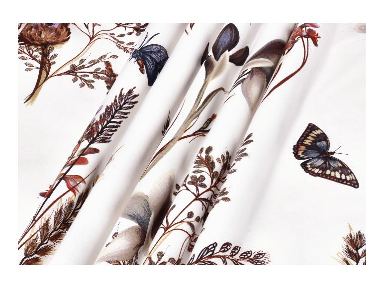 Tissu blanc avec un motif floral et de papillons dans des tons terreux.