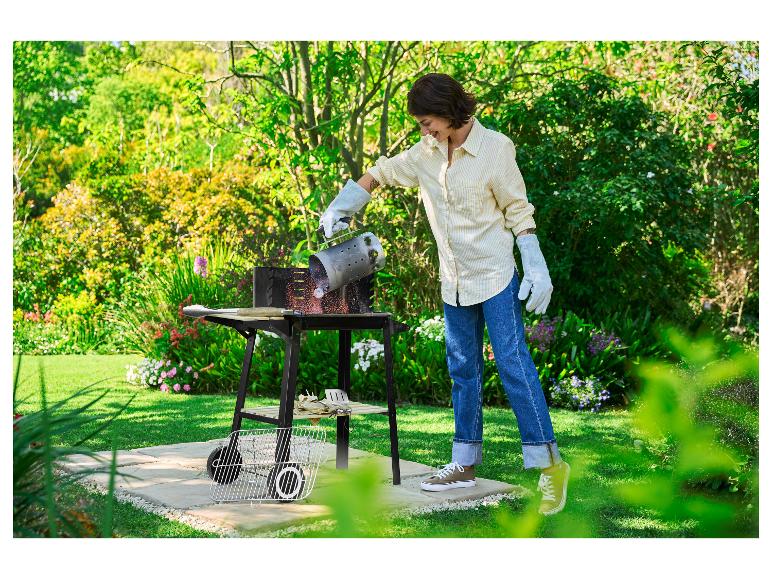 Femme versant du charbon de bois incandescent d'une cheminée d'allumage dans un barbecue.