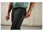 Homme portant un pantalon de survêtement noir avec un smartphone dans la poche.