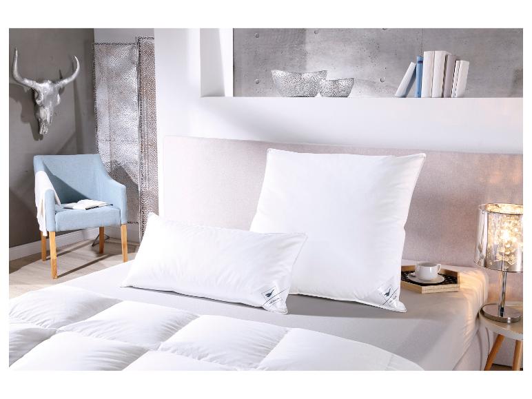 Chambre avec literie blanche, oreillers et couette, une chaise bleu clair et une décoration murale argentée.