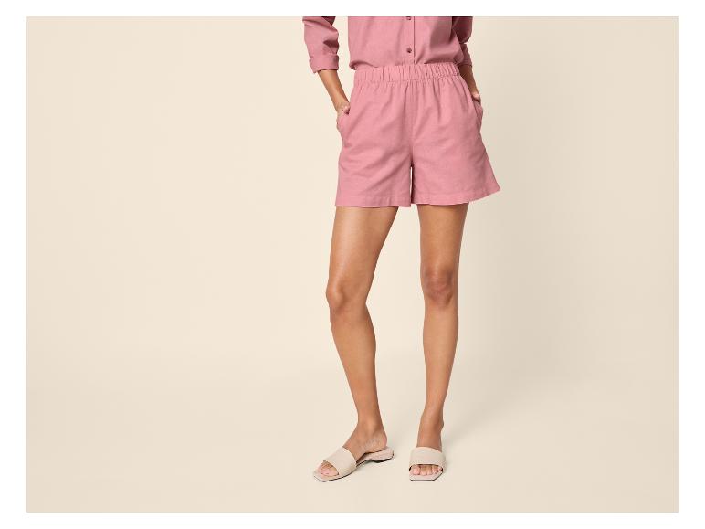 Femme en chemise et short roses, avec des sandales beiges.