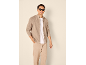 Homme portant un gilet en maille beige zippé, un t-shirt blanc et un pantalon assorti.