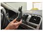 Des mains installent un support de téléphone portable pour voiture dans une grille d'aération.