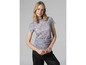 Une femme portant un t-shirt gris à imprimé et un pantalon noir.