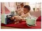 Deux enfants jouent avec des appareils de cuisine jouets, dont un four et une casserole.
