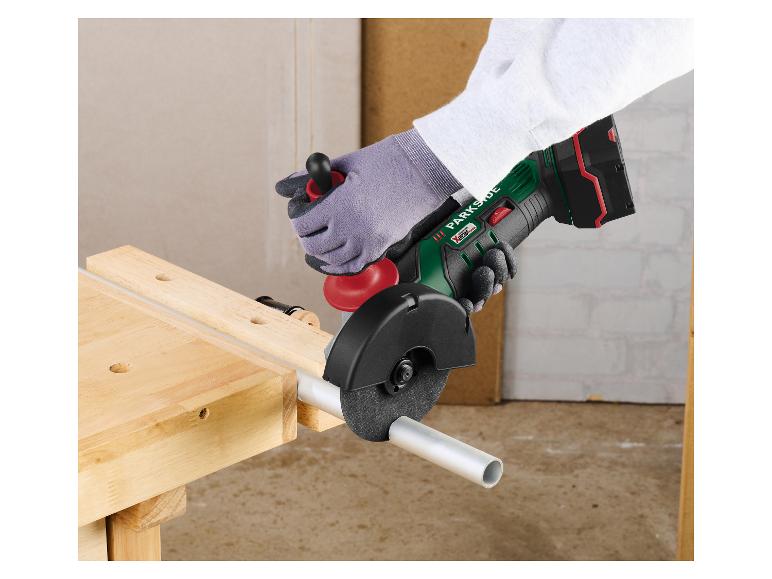 Meuleuse d'angle sans fil Parkside coupant un tuyau métallique sur un établi en bois.
