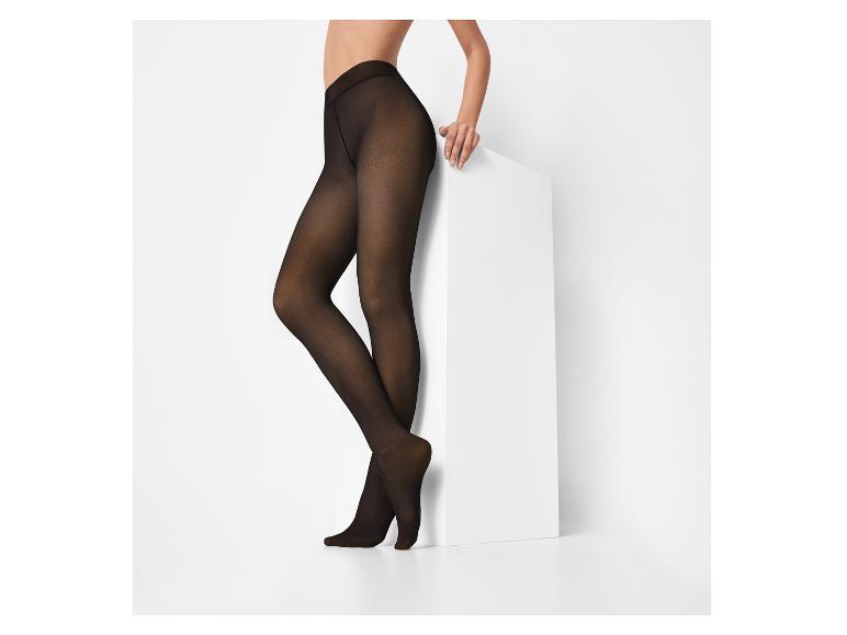 Femme portant des collants noirs opaques, appuyée sur un piédestal blanc.