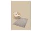 Fauteuil en osier avec coussins crème et tapis à motif géométrique sur fond beige.