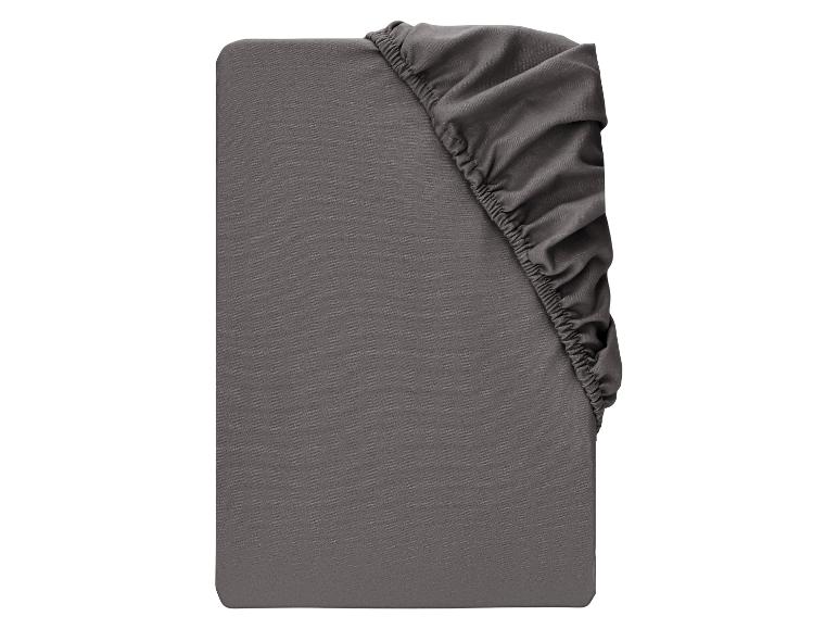 Drap-housse gris foncé avec élastique dans le coin supérieur droit.