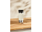Mug isotherme crème avec couvercle noir et grains de café sur une surface en bois.