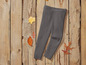 Leggings grises en tricot sur un fond en bois avec des feuilles d'automne.