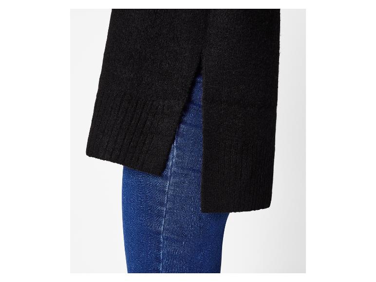 Pull noir à fentes latérales porté sur un jean bleu