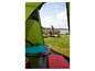 Un sac de couchage et un matelas dans une tente verte avec vue sur un lac.