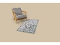 Fauteuil gris avec cadre en bois et tapis gris à motifs sur fond beige.