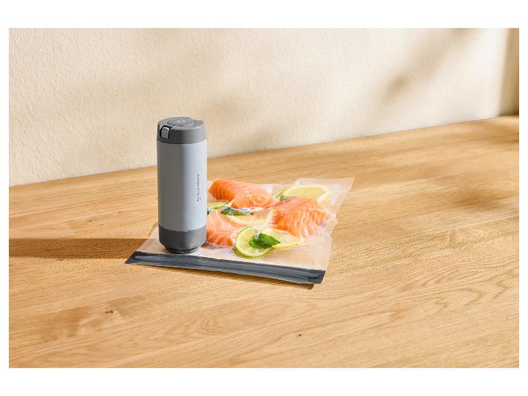 Scelleuse sous vide Silvercrest et sac sous vide avec saumon, citron et menthe sur une planche en bois.