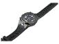 Une montre-bracelet noire avec un bracelet texturé et une petite lampe de poche sur le côté.