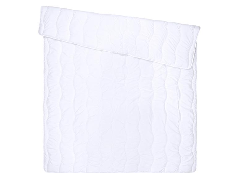 Couette blanche matelassée, pliée en haut, sur fond blanc
