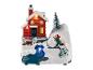 Une décoration de Noël avec une maison rouge, un sapin et un enfant qui lance une boule de neige.