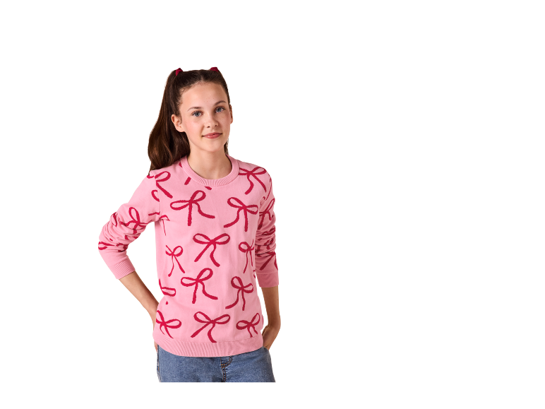 Une fille en pull rose avec un motif de nœuds et un jean bleu