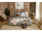 Chambre chaleureuse aux tons beiges avec un lit double paré de linge de lit gris.