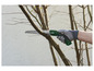Une main utilisant une scie Parkside pour couper une branche d'arbre.