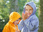 Deux enfants en imperméables, l'un en bleu, l'autre en jaune, jouent sous la pluie.