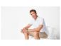 Homme en polo blanc et short beige assis sur une chaise blanche