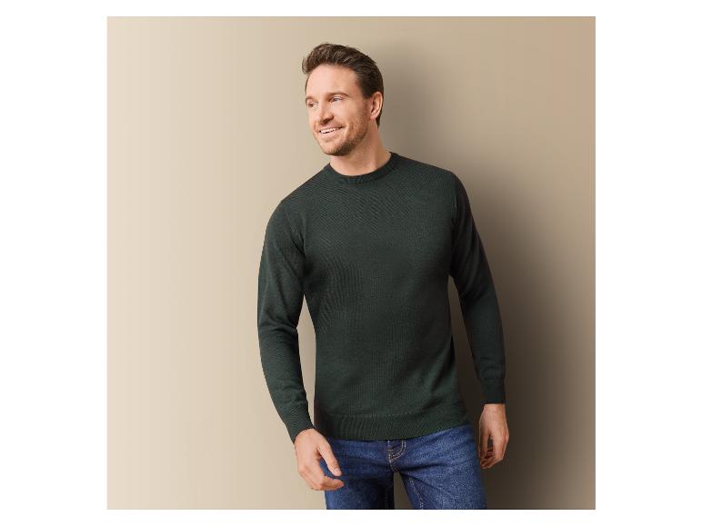 Homme portant un pull vert foncé et un jean bleu.