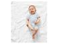 Bébé souriant sur un plaid blanc, vêtu d'une grenouillère.