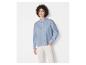Une femme portant une chemise bleu clair et un pantalon blanc.