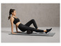 Une femme en tenue de sport utilise un rouleau en mousse sur un tapis.