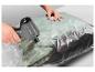 Mains utilisant une pompe à vide électrique pour emballer des vêtements dans un sac sous vide.