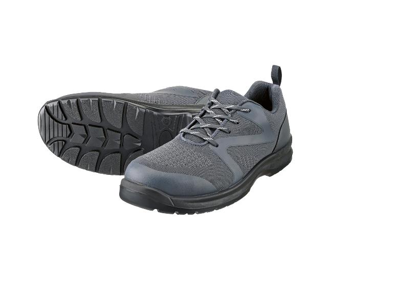 Une paire de chaussures de travail grises à lacets, une chaussure est sur le côté montrant la semelle.