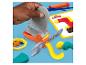 Main tenant une scie jouet avec de la pâte à modeler colorée et d'autres outils de jeu.