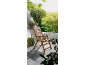 Chaise pliante en bois sur une terrasse, ambiance jardin.