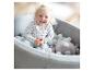 Un enfant dans une piscine à balles avec des balles blanches et un jouet en peluche gris.