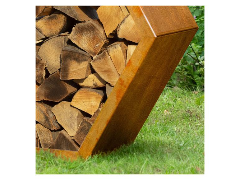 Bois de chauffage empilé dans un support métallique sur une pelouse.