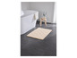 Un tapis de bain beige à motifs losanges dans une salle de bain avec une baignoire.
