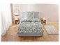 Parure de lit fleurie en vert et beige sur un lit gris.