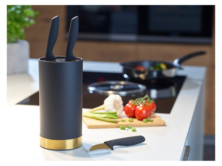 Un bloc à couteaux noir avec une bordure dorée et des couteaux dans la cuisine.