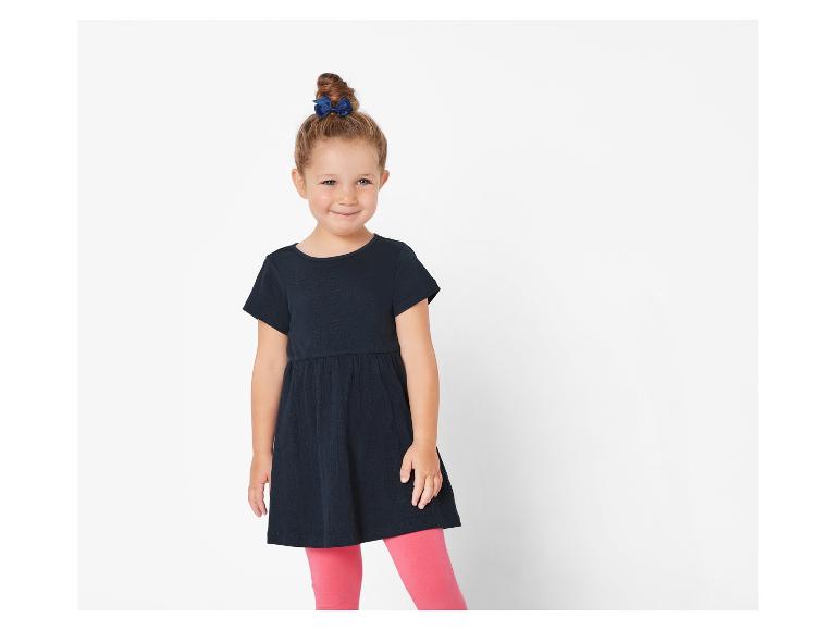 Une fille portant une robe noire avec des leggings roses.