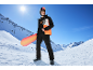 Homme en veste et pantalon de snowboard, casque, lunettes, tenant un snowboard sur fond de montagne enneigée.