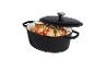 Cocotte ovale en fonte noire avec couvercle, remplie de poulet rôti et de légumes.