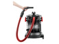 Un aspirateur noir avec un tuyau rouge et une main tenant le tuyau.