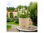 Pot de fleurs beige avec plantes blanches sur une table en mosaïque dans un jardin.