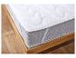 Un matelas blanc avec un dessous gris sur un cadre de lit en bois.