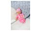 Une poupée Baby Born rose avec un bonnet sur un lit blanc